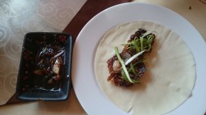 la peau croustillante du canard est dégustée avec de la cive dans une galette de riz